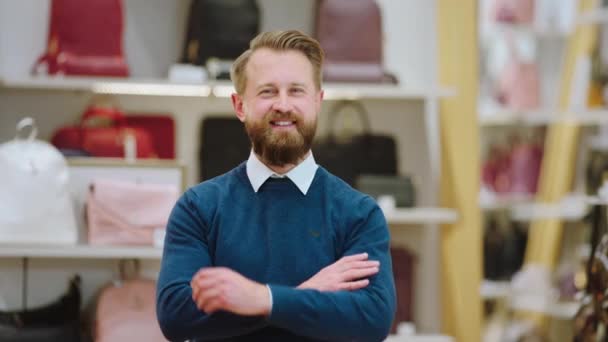 Un supervisor guapo posando delante de la cámara sonriendo a lo grande en medio de la tienda de accesorios. Disparo en ARRI Alexa Mini. — Vídeo de stock