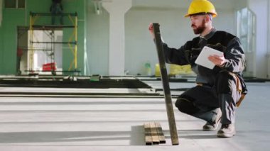 Modern inşaat sahasında inşaat işçisi inşaat malzemelerinin kodlarını yazmak için dijital tablet kullanıyor.