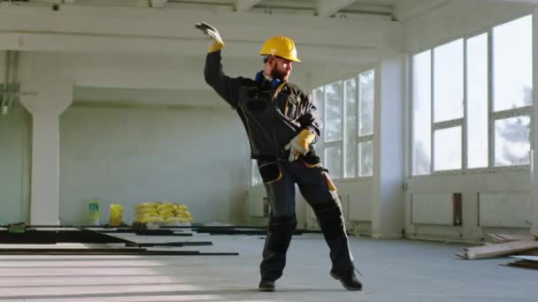 在建筑工地结束一天的工作后，英俊的戴安全帽和安全设备的工程师兴奋地跳着迷人的舞。向ARRI Alexa Mini开枪. — 图库视频影像