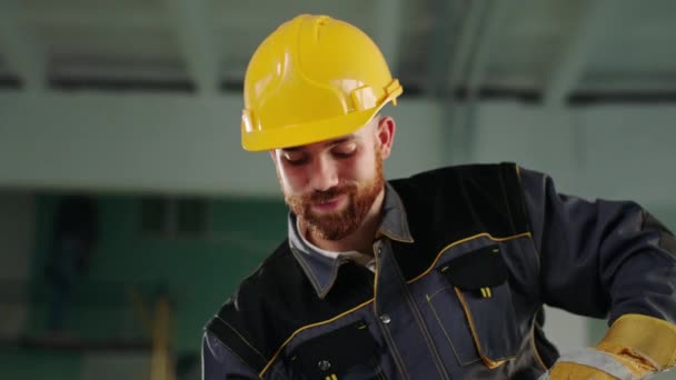 Güvenlik kaskı ve üniforması olan büyük bir inşaat işçisi, inşaat alanında çalışıyor ve anın tadını çıkarıyor. — Stok video