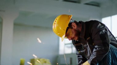 Disk kaynak makinesini kullanarak metalleri kesen ve inşaat alanında büyük bir kıvılcım yaratan konsantre bir adamın portresi.