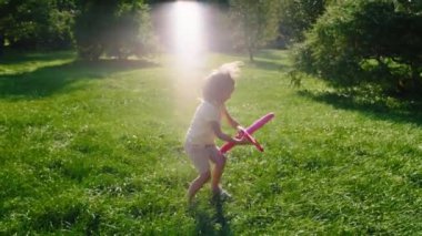Parkın ortasında uçakla sert oynayan tatlı çocuk çimlerin üzerinde koşuyor. ARRI Alexa Mini 'de çekilen.