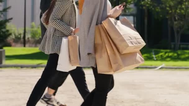 Uśmiechnięta grupa biznesmenek z torbami na zakupy spacerująca po nowoczesnym mieście ze szczegółami trzech kobiet — Wideo stockowe
