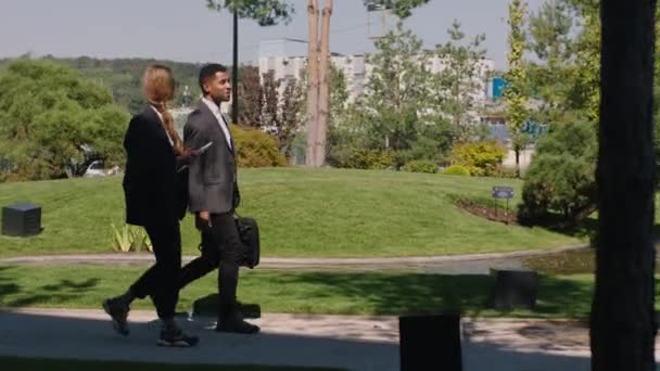 현대 대학 공원에서 아름다운 두 학생 과 카리스마있는 흑인 남자가 함께 걷고 나서 함께 대화를 나눕니다. — 비디오