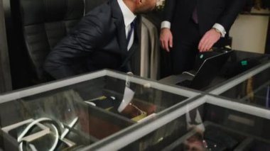 Lüks kostüm dükkanındaki iki işadamı el sıkışıyor ve gülümsüyor. Küçük işletmeler ve tasarımlar.