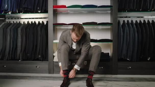 Modern and luxury suit shop Caucasian businessman take a new pair of leather shoes and wear them in front of the camera — Stock Video