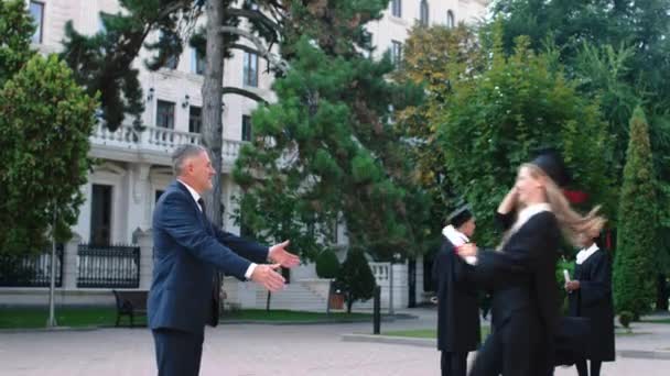 Impresionante mujer que mira corriendo con su diploma después de que ella se graduó a su padre abrazando juntos comienzan a discutir juntos — Vídeos de Stock