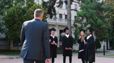 Modern üniversite parkında, üniversite profesörü mezuniyetten sonra öğrencilerine yürür ve onları tebrik eder. Hepsi mutlu ve heyecanlıdır.