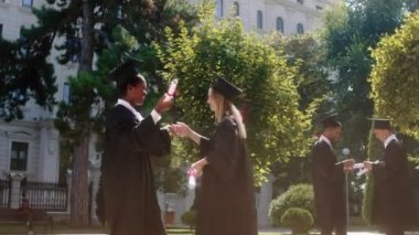 Çok ırklı mezunlar iki güzel bayan mezun olduktan sonra birbirlerini tebrik ettiler. Heyecanlı ve mutlu bir geçmişleri var. Diğer öğrenciler hep birlikte tartışarak mezun oluyorlar.