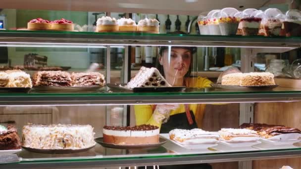 Concept of small business restaurant and food in the coffee shop pretty woman owner of the cafe with protective mask carefully arrange the deserts from the showcase fridge — Stock Video