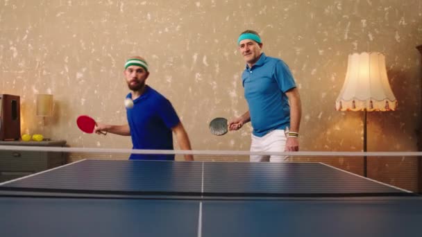 Dva charismatičtí muži jeden mladý a jeden starý šťastný hrát stolní tenis nebo ping pong oni bít míč s raketou a objímat jeden druhého — Stock video