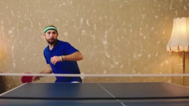 Ping pong oynayan yakışıklı bir adam konsantre oldu. Ev yapımı sağlıklı yaşam tarzı ve spor kavramında kırmızı raketlerle topları yakaladı.