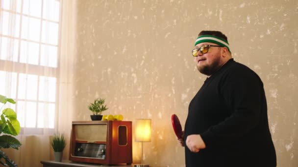 Charismatic fat man doing sport at home he playing the ping pong at home very excited he catch the ball with the racket and get excited he wearing the sun glasses. Shot on ARRI Alexa Mini — Vídeo de Stock