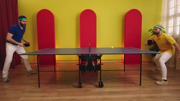 Charismatic two guys full equipment in the uniform playing the table tennis or ping pong game they catch the balls and hitting with the paddles. Shot on ARRI Alexa Mini — Stockvideo