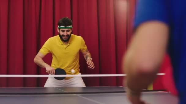 卓球の試合で友達と遊んでいる大きな笑顔の男とハンサムな彼はボールをキャッチし、同時に打つ卓球の制服を着ています。ARRIアレクサミニで撮影 — ストック動画