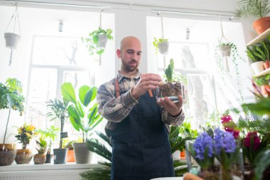 Çiçekçide çiçekçi çok yakışıklı bir adam dükkânda çiçekçi konseptine bakıyor.