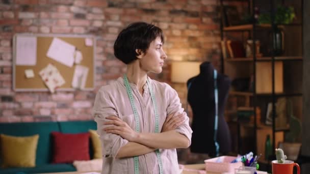 Beautiful Caucasian woman dressmaker at her modern tailoring atelier posing in front of the camera smiling large and feeling relaxed at her workplace — Vídeo de Stock