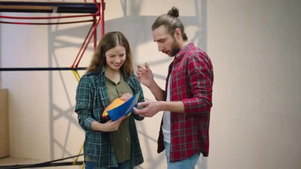 Dobře vypadající pár s velkým úsměvem společně analyzující barevnou paletu pro malování stěn doma diskutují společně — Stock video