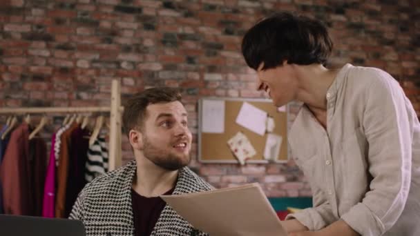 A handsome man and woman are working through things on the laptop and laughing together — Vídeo de Stock