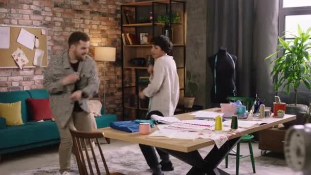 Two charismatic people are dancing and enjoying eachothers company as they dance around in the designer home office — Stock Video
