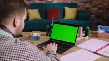 Modern terzilik atölyesi yeşil masaüstü bilgisayarı kullanıyor. Bilgisayardan bazı müşteri ölçümlerini analiz ediyor.