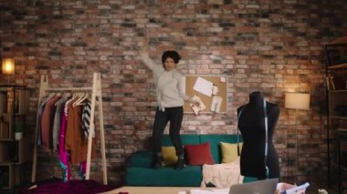 Küçük işletme atölyesi tasarımı. Güzel kadın moda tasarımcısı. Ofisinde dans ediyor.