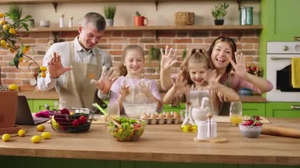 Перед камерой харизматичная счастливая и улыбающаяся большая семья готовит вкусное тесто для печенья вместе все они пожимают руки перед камерой и улыбаются широко. Снимок на ARRI Alexa Mini — стоковое видео