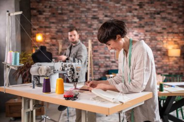 Tasarımcı görünümlü bir ofiste bir erkek ve kadın dizüstü bilgisayarda çalışıyor ve tartışırken gülüyorlar, ortam çok serin.
