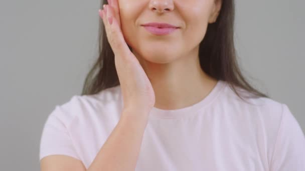 En el fondo blanco tomando video primer plano de la mujer masajear su cara y luego sonriendo grande que sostiene de pequeña crema hidratante concepto de tratamiento de cosméticos de la piel saludable y cuidado de la piel. Disparo en ARRI — Vídeos de Stock