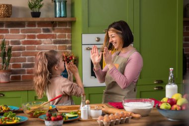 Heyecanlı beyaz aile babaları ve iki çocuk, kırsal mutfak adasında birlikte yemek yapmaya başlamadan önce taş kağıt makas oynamaktan mutlu olurlar.