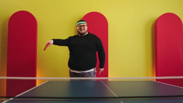 Rolig fet kille gör dig redo att spela på ping pong han dansar och flytta karismatisk all utrustning som håller racket på händerna — Stockvideo