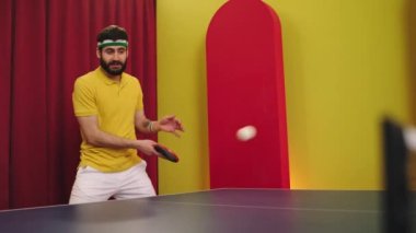 Spor anlayışı ve sağlıklı yaşam tarzı üniformalı, masa tenisi oynayan karizmatik adam topları yakalar ve dikkatle vurur.
