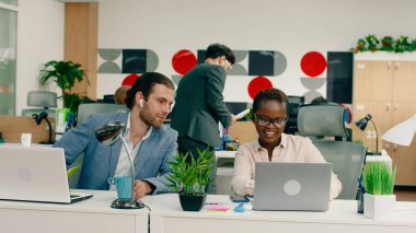 Yakışıklı esmer bir adam ve güzel sarışın bir kadın ofiste masalarında iş yapıyorlar, melez bir siyah adam ortaya çıkıyor ve onlarla konuşuyor ve sonra başka bir beyaz adam gelip bir parça bırakıyor.