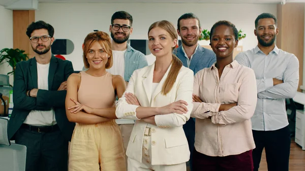 Eine Gruppe Arbeiter starrt direkt in die Kamera, während sie die Arme verschränkt haben und in einer Formation mit einer schönen Frau an der Spitze stehen. — Stockfoto