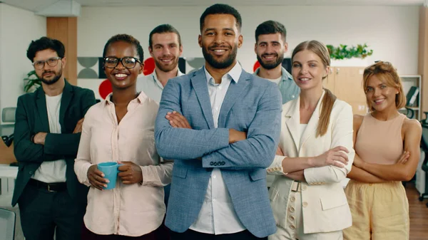 Grupa współpracowników jest w bardzo ładnym biurze, uśmiecha się i krzyżuje ramiona wyglądając na zadowolonych. — Zdjęcie stockowe