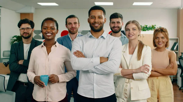 Un gruppo di persone diverse e uniche sono in un ufficio dall'aspetto moderno tutti sorridenti, in piedi in un unico luogo e guardando la fotocamera — Foto Stock
