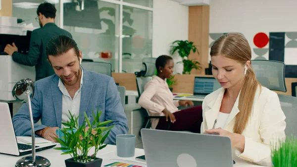 Un uomo e una donna sono al lavoro a parlare di affari, sembrano entrambi abbastanza felici, sono in ufficio che ha un'atmosfera vivace. — Foto Stock