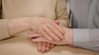 Taking video closeup details of old couples hands hugging each other very carefully with love