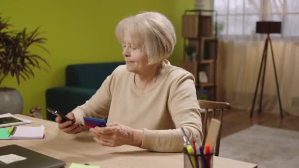 Yaşlı kadın internet üzerinden ödemeyi mutlu ediyor. Kredi kartını kullanarak kredi kartı numarasını yazıyor. — Stok video