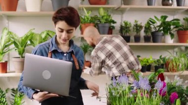 Çiçekçide güzel karizmatik bir çift var. Dükkan sahipleri birlikte çalışıyorlar. Dizüstü bilgisayarı kullanıyorlar.