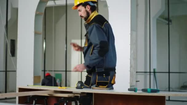 Travailleur constructeur attrayant et excité sur le chantier de construction concentré il danse et fait quelques mesures en même temps porter un casque de sécurité et uniforme — Video