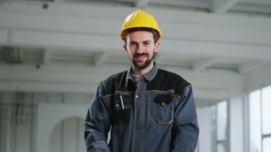 Yakışıklı inşaatçı el ele tutuşup kameranın önünde karizmatik pozlar veriyor. Güvenlik kaskı takıyor.