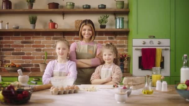 Geweldige tijd doorbrengen in de keuken poseren voor de camera gelukkig glimlachen grote moeder en haar twee kinderen kruisen handen en recht kijken — Stockvideo