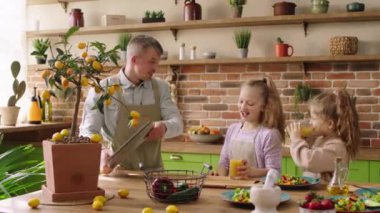 Good looking family charismatic man together with his daughter have fun in the morning before going to work and school they prepare breakfast together dad take his watering pan and drizzle his kids