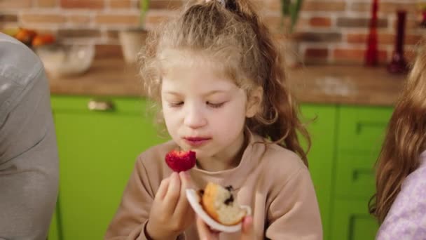 キッチンの近くのきれいな女の子は台所の島で朝の健康的な朝食を取るかわいい女の子おいしいいくつかのイチゴ — ストック動画