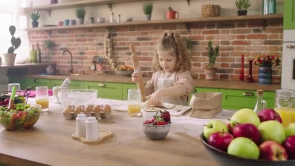 Charismatic and beautiful girl at the kitchen island alone preparing the dough for a delicious dessert to cook she take some flour and put over the dough — Stock Video