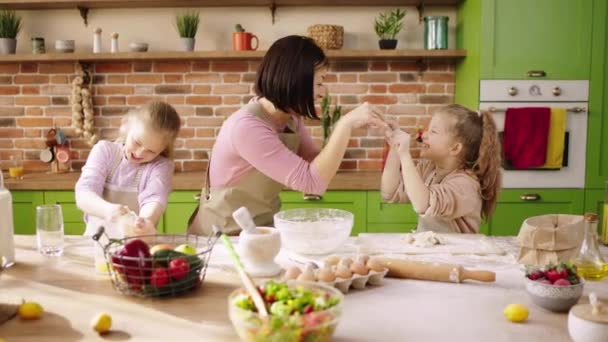 Ibu karismatik dan putri-putrinya yang cantik menghabiskan waktu bersama sambil menyiapkan makanan penutup lezat ibu mengambil beberapa tepung dan bermain dengan putri kecilnya — Stok Video