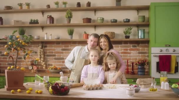 Biała rodzina bardzo podekscytowany z dwójką uroczych dzieci pozowanie przed kamerą w domu w dużej świetlistej kuchni mają duży uśmiech — Wideo stockowe