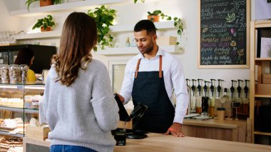 Terminal masasında çalışan Afro-Amerikan kahve dükkanındaki kameranın önünde müşteri bayanla tartışıyor ve siparişi alıyor.