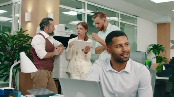 Two bearded men in their work suits are talking to a blonde woman holding a tablet in her white suit, they re in the office conversing about their work — Stockvideo